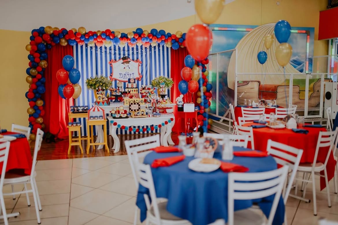 Salão decorado com tema circo, mesas postas e balões