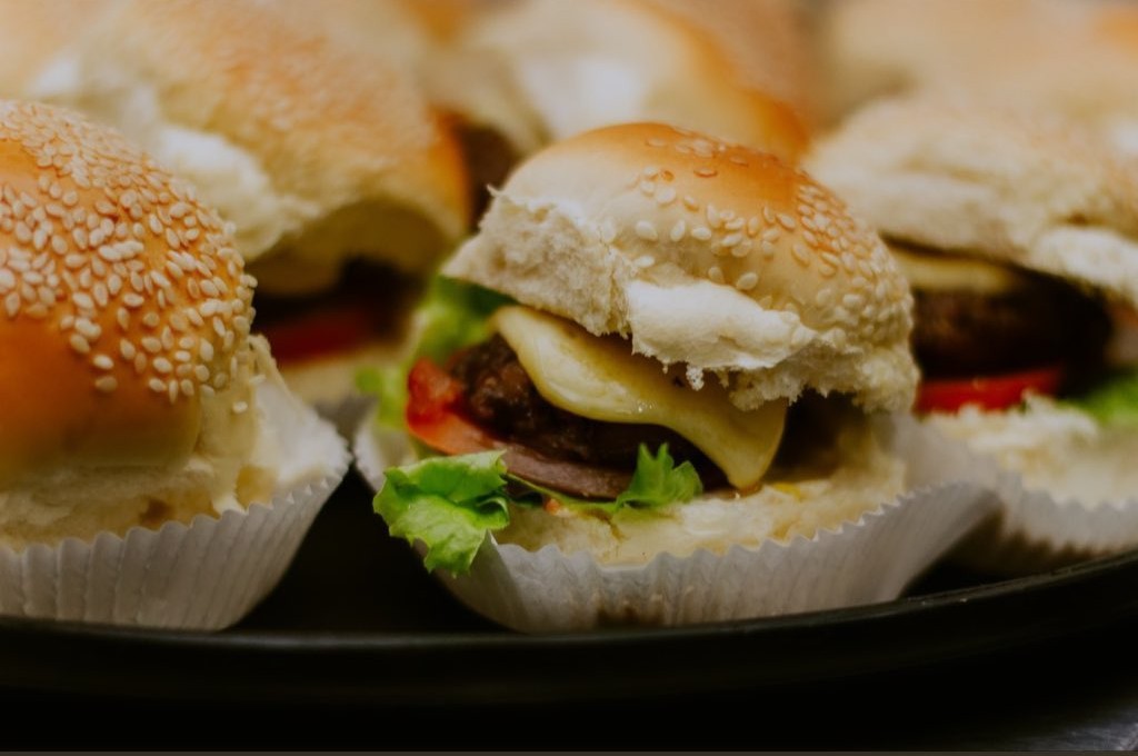 Mini hambúrgueres com queijo, alface e tomate servidos na festa